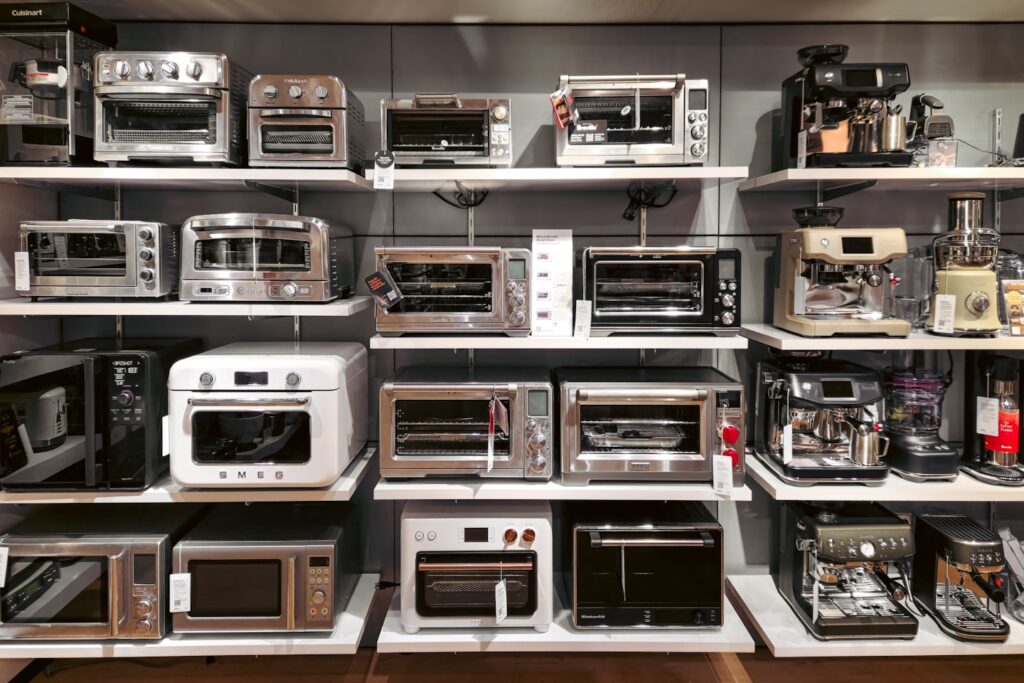This image captures a store display with shelves stocked with toaster ovens and coffee machines, showcasing a variety of kitchen appliances.